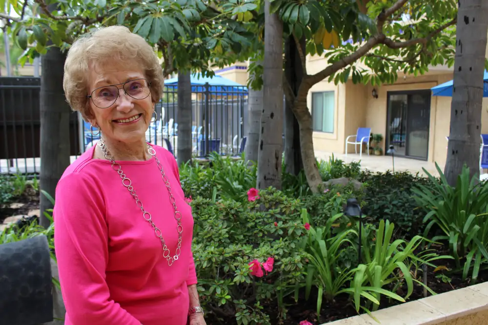 Freedom Village resident standing outside by the pool and garden