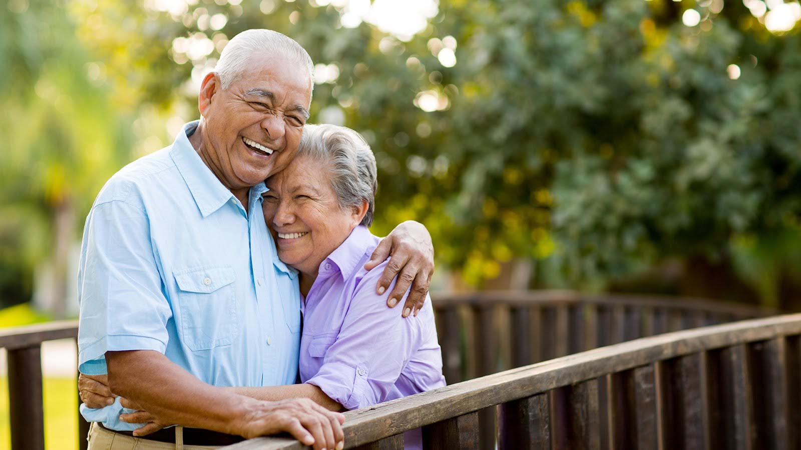 senior couple laughing together on bridge.